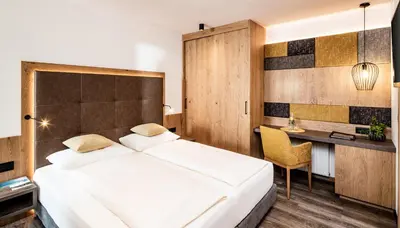 a bedroom with a large bed and a desk at Hotel Krause in Tirolo