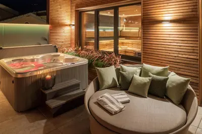 a room with a tub and a chair with a table at Hotel Krause in Tirolo