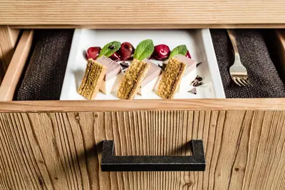 a wooden box with food on a plate with a letter l at Hotel Krause in Tirolo