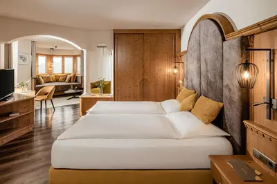 a bedroom with two beds and a living room at Hotel Krause in Tirolo