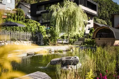 a garden with a pond in front of a building at Bachmannhof in Feldthurns