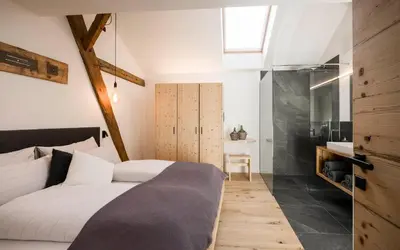 a bedroom with a large white bed and a bathroom at Bachmannhof in Feldthurns