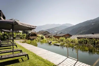 a patio with benches and an umbrella next to a river at Bachmannhof in Feldthurns