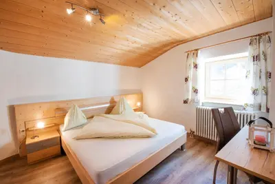 a bedroom with a bed and a desk and a window at Gartenheim Ferienwohnung in Caldaro