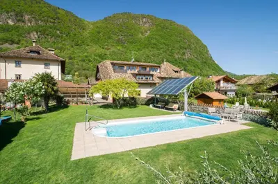 a yard with a swimming pool in front of a house at Gartenheim Ferienwohnung in Caldaro