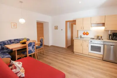 a kitchen and living room with a table and a kitchen and a dining room at Gartenheim Ferienwohnung in Caldaro