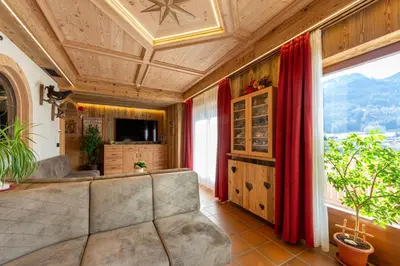 a large room with a bar with wooden ceilings at Hotel Villa Jolanda in Ziano di Fiemme
