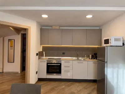 a kitchen with white cabinets and a microwave at Appartamenti LITEGOSA casa vacanza 3 in Panchia