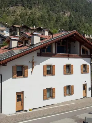 a white building with wooden windows and a mountain at Appartamenti LITEGOSA casa vacanza 3 in Panchia