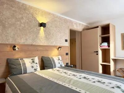a bedroom with a bed and a light on the wall at Appartamenti LITEGOSA casa vacanza 3 in Panchia