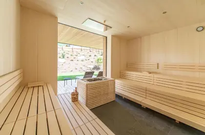 a sauna with wooden benches and a large window at Linara Mountain Family Stay in Valles