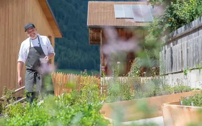 a man wearing an apron standing in a garden at Linara Mountain Family Stay in Valles