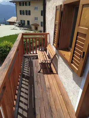 a wooden bench sitting on a balcony next to a door at Casa Vacanze Fontana in Coredo