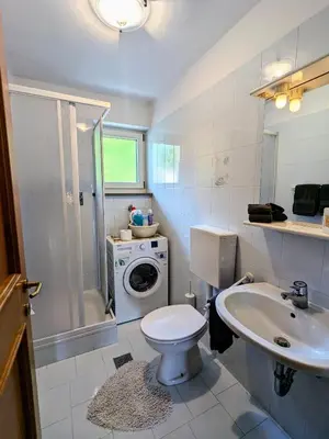 a bathroom with a toilet and a sink and a washing machine at Casa Lagoraiview in Carano