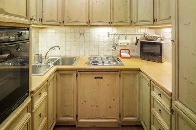 a kitchen with wooden cabinets and a sink and a microwave at Villa Ronco - Stayincortina in Cortina dʼAmpezzo