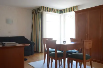 a living room with a table and chairs and a window at Hotel Tannerhof in Schenna