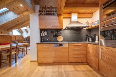 a kitchen with wooden cabinets and a dining room at Attic Apartment Dolasilla in Selva di Val Gardena