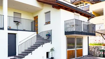 a white house with black railing and stairs at Ferienwohnung Bergblick in Termeno