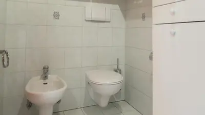 a white bathroom with a toilet and a sink at Ferienwohnung Bergblick in Termeno