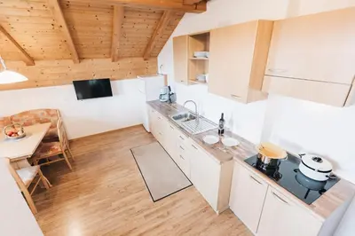 a kitchen with white cabinets and a wooden floor at Weißhaus Hof in Caldaro