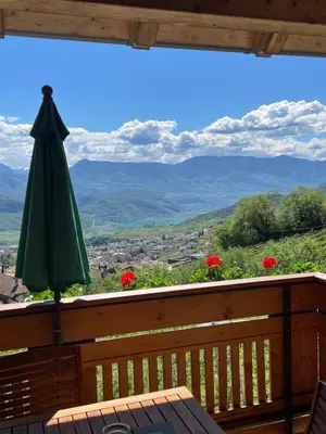 an umbrella and a table on a balcony with a view at Weißhaus Hof in Caldaro