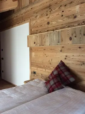 a bedroom with a bed with a wooden wall at B&B Belvedere in Daiano