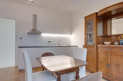 a kitchen with a wooden table and white chairs at Frida's apartment in Merano