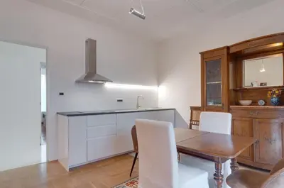 a kitchen with a wooden table and white chairs at Frida's apartment in Merano
