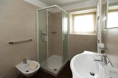 a bathroom with a shower and a toilet and a sink at Appartamenti Genziana in La Villa