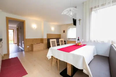 a dining room with a white table with a red napkin at Appartamenti Genziana in La Villa