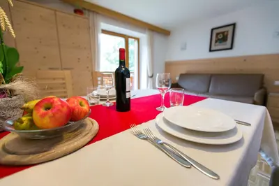 a table with a bowl of apples and a bottle of wine at Appartamenti Genziana in La Villa