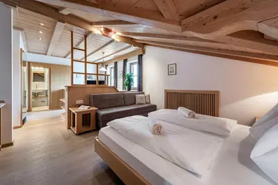 a bedroom with a large bed and a couch at Hotel Restaurant Waldea in Marlengo