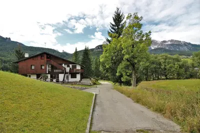 a house on a hill next to a dirt road at Appartamento Croda in Cortina dʼAmpezzo