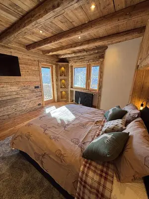 a bedroom with a large bed in a room with wooden ceilings at Luxury Central Apartment Cortina D'Ampezzo in Cortina dʼAmpezzo