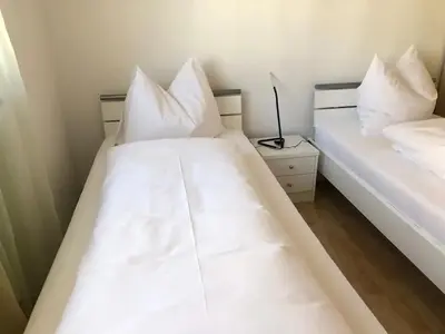 two beds in a room with white sheets and pillows at A&A Apartments Resort in Bressanone