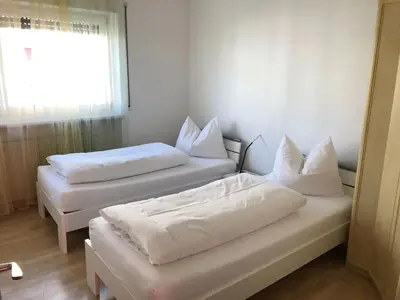 two beds with white pillows in a room with a window at A&A Apartments Resort in Bressanone