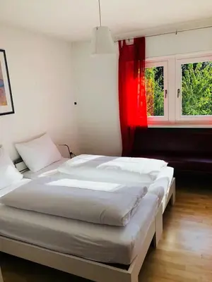 a bedroom with two beds and a red window at A&A Apartments Resort in Bressanone