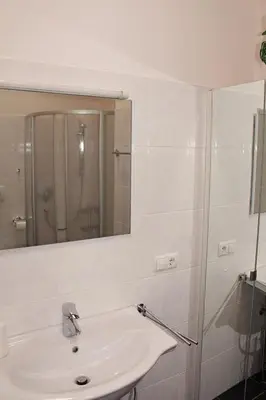 a white bathroom with a sink and a shower at FeWo 3 am Martinshof in Eppan im Süden Südtirols in Missiano