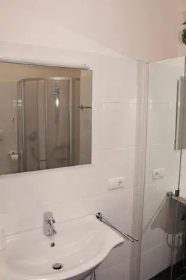 a white bathroom with a sink and a mirror at FeWo 2 am Martinshof in Eppan im Süden Südtirols in Missiano
