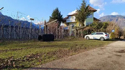 a white car parked in a yard next to a house at FeWo 2 am Martinshof in Eppan im Süden Südtirols in Missiano