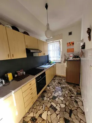 a kitchen with wooden cabinets and a stone floor at Appartamento nelle Dolomiti 900 mt dallo stadio del salto in Predazzo