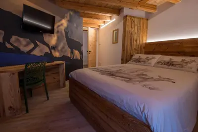 a bedroom with a bed and a desk with a tv at Mas di Siti in Castelfondo