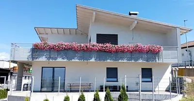 a white building with pink flowers on a balcony at Grande appartamento indipendente in Coredo
