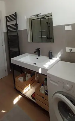 a bathroom with a sink and a washing machine at Grande appartamento indipendente in Coredo