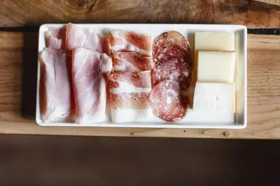 a plate of food with meat and cheese on a table at Der Unterwirt Guesthouse - Pool & JRE Restaurant in Chiusa