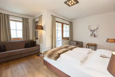 a bedroom with a large bed and a couch at Der Unterwirt Guesthouse - Pool & JRE Restaurant in Chiusa