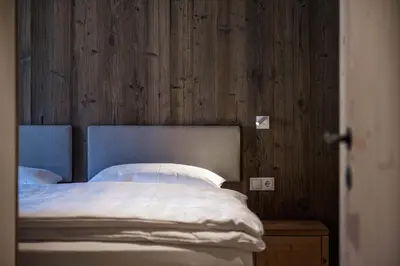a bedroom with a bed with a wooden wall at Ansitz Pontegardena in Ponte Gardena