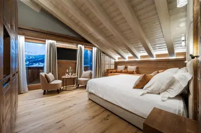 a bedroom with a large bed and a large window at Casa Guargnè in Cortina dʼAmpezzo