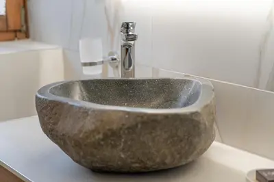 a bathroom with a stone sink with a faucet at Apartment with Sauna at Pineta Pastry in Sottoguda