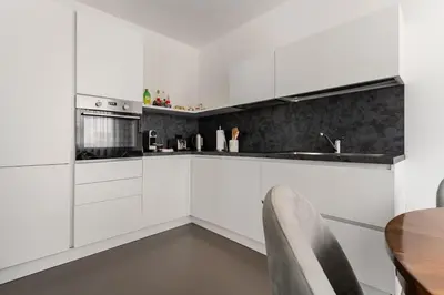 a kitchen with white cabinets and a wooden table at Heart Apartment in Merano